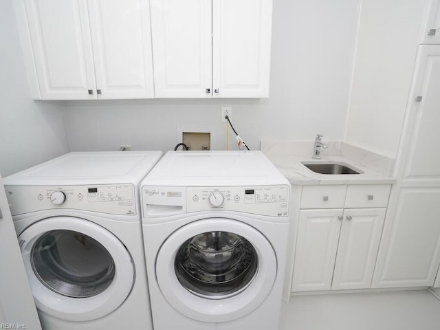 clothes washing area with cabinets, washer and dryer, and sink