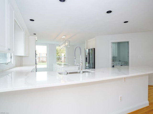 kitchen featuring stainless steel fridge, white cabinetry, sink, and light hardwood / wood-style flooring