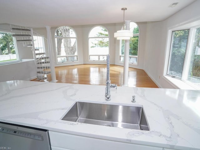 kitchen featuring pendant lighting, dishwasher, light hardwood / wood-style floors, sink, and ornate columns