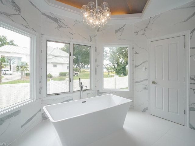 bathroom with a notable chandelier, a washtub, and a wealth of natural light