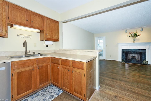 kitchen with sink, a high end fireplace, kitchen peninsula, stainless steel dishwasher, and dark hardwood / wood-style floors