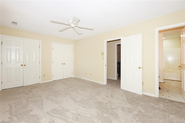 unfurnished bedroom featuring ceiling fan, light colored carpet, and multiple closets