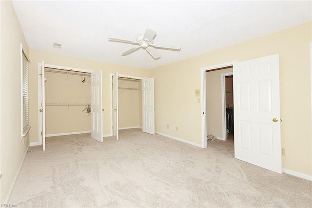 unfurnished bedroom with ceiling fan, two closets, and light carpet