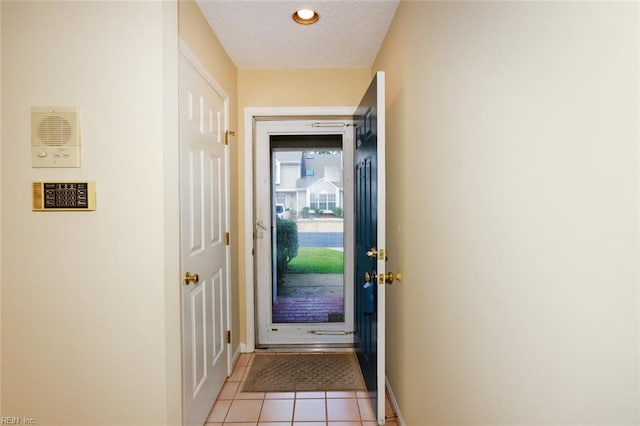 doorway featuring a textured ceiling and light tile patterned flooring