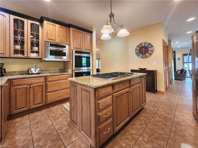 kitchen featuring dark tile patterned flooring, a chandelier, light stone counters, hanging light fixtures, and appliances with stainless steel finishes