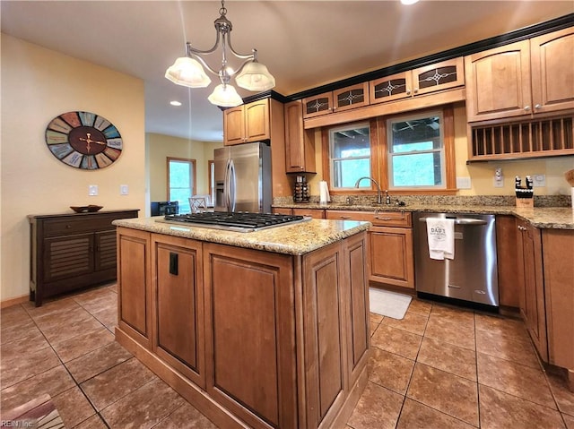 kitchen featuring sink, dark tile patterned floors, decorative light fixtures, stainless steel appliances, and a center island