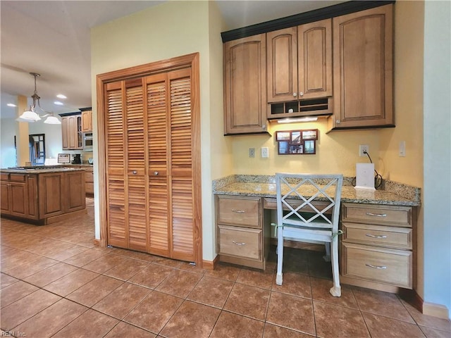 kitchen featuring an inviting chandelier, pendant lighting, dark tile patterned floors, and light stone counters