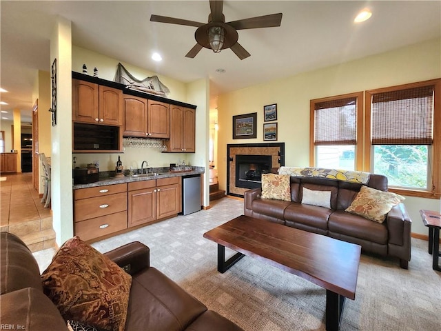 carpeted living room with ceiling fan, a fireplace, and sink