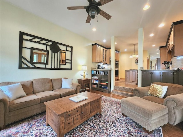 living room with wood-type flooring and ceiling fan with notable chandelier