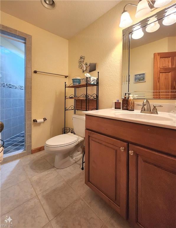 bathroom featuring tile patterned flooring, walk in shower, vanity, and toilet