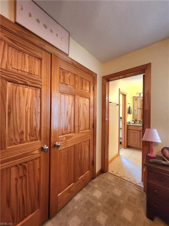 corridor featuring a textured ceiling and light colored carpet