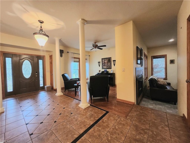 entryway with ceiling fan, dark tile patterned floors, and ornate columns