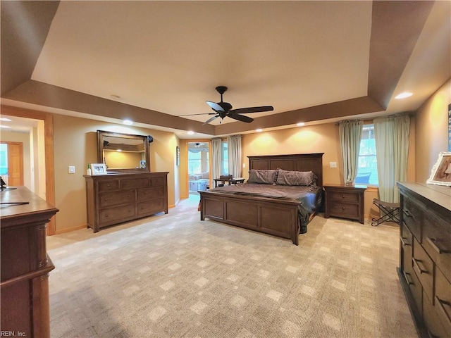 carpeted bedroom with ceiling fan and a tray ceiling