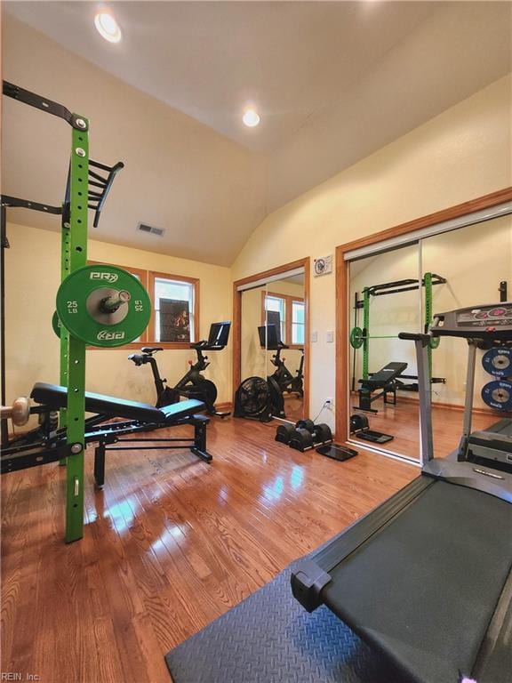 exercise room with vaulted ceiling and hardwood / wood-style flooring