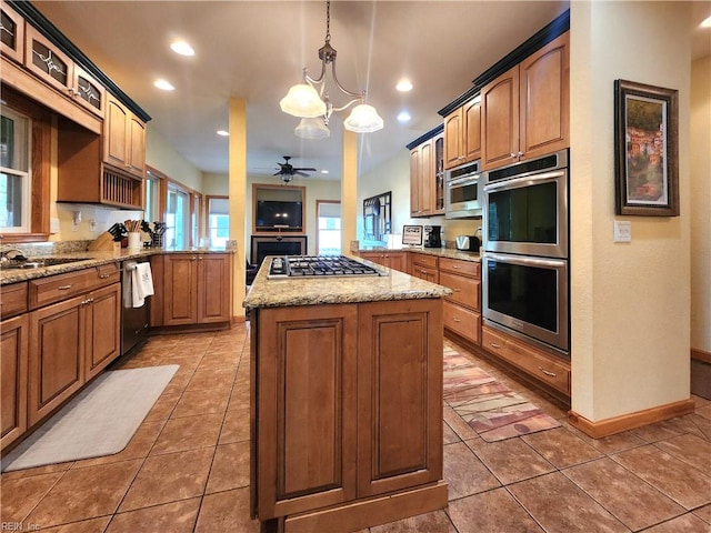 kitchen featuring a kitchen island, decorative light fixtures, stainless steel appliances, ceiling fan with notable chandelier, and tile patterned flooring