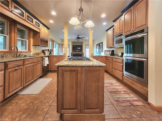 kitchen featuring sink, ceiling fan with notable chandelier, hanging light fixtures, a kitchen island, and appliances with stainless steel finishes