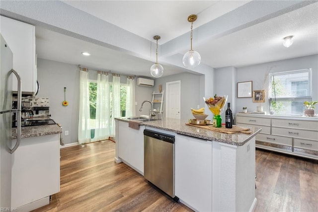 kitchen with wood-type flooring, dishwasher, a wall unit AC, white cabinetry, and decorative light fixtures