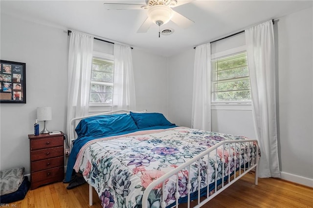 bedroom featuring wood-type flooring, multiple windows, and ceiling fan