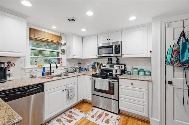 kitchen with light hardwood / wood-style flooring, white cabinetry, appliances with stainless steel finishes, and sink