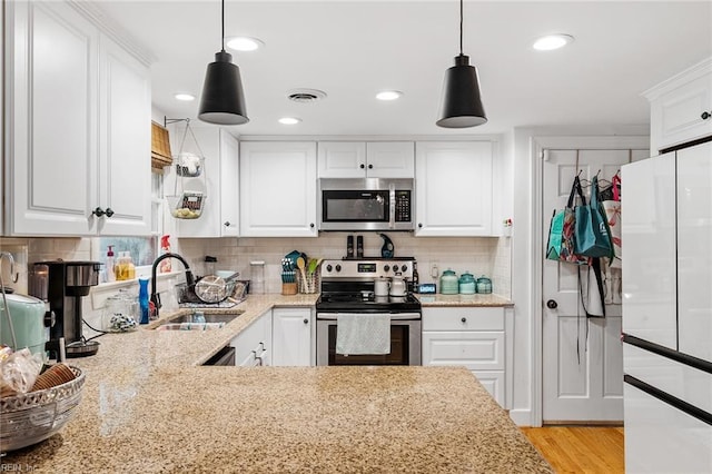 kitchen with appliances with stainless steel finishes, white cabinetry, and decorative light fixtures