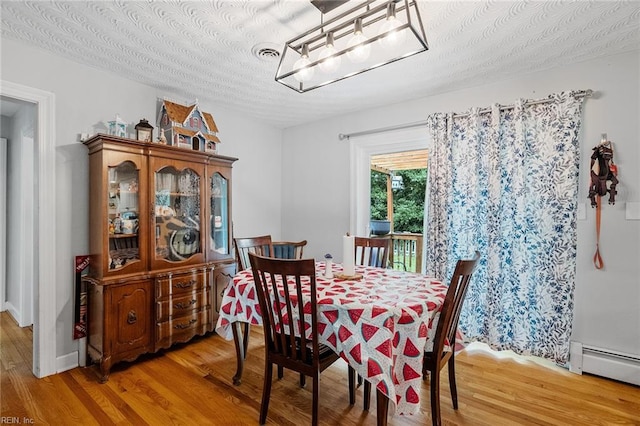 dining space with a textured ceiling, a baseboard heating unit, and hardwood / wood-style flooring