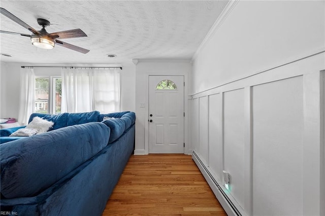 entrance foyer with a baseboard radiator, ornamental molding, ceiling fan, and hardwood / wood-style flooring