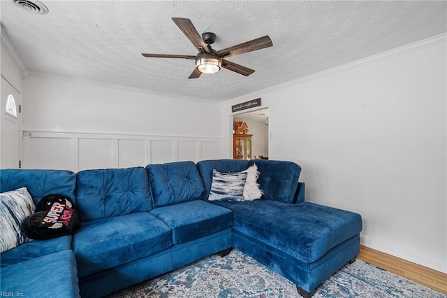 living room featuring a textured ceiling, wood-type flooring, crown molding, and ceiling fan