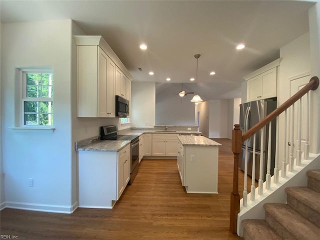 kitchen with a center island, dark wood-type flooring, white cabinetry, stainless steel appliances, and light stone countertops