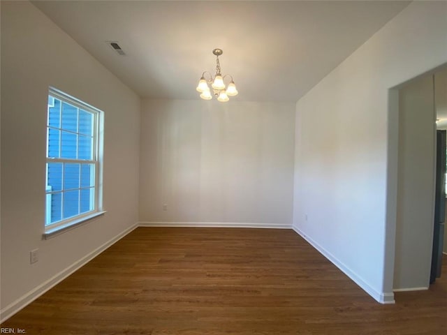 spare room with dark hardwood / wood-style floors and a chandelier