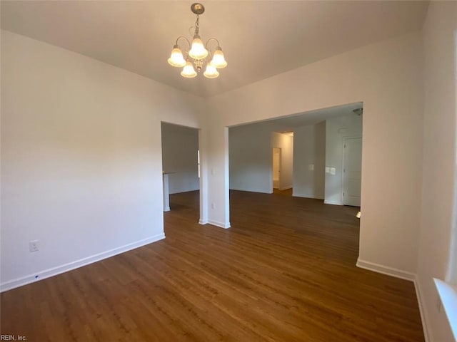 unfurnished room with an inviting chandelier and dark hardwood / wood-style floors