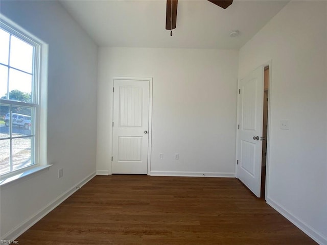 unfurnished room featuring a wealth of natural light, ceiling fan, and dark hardwood / wood-style flooring