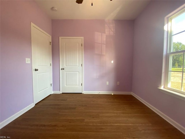 unfurnished room featuring ceiling fan, dark wood-type flooring, and a healthy amount of sunlight