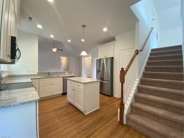 kitchen with appliances with stainless steel finishes, a center island, sink, and white cabinets