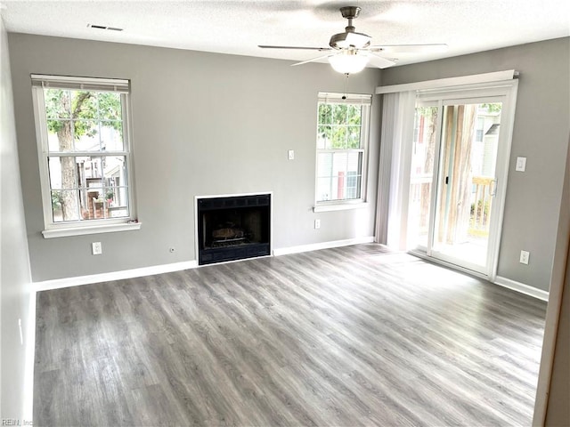 unfurnished living room featuring ceiling fan, a textured ceiling, light wood-type flooring, and a healthy amount of sunlight