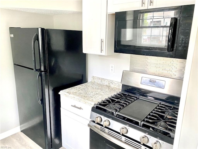 kitchen featuring black appliances, light stone counters, and white cabinets