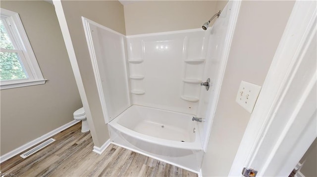 bathroom featuring shower / bathtub combination, wood-type flooring, and toilet