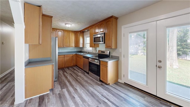 kitchen with sink, light hardwood / wood-style flooring, stainless steel appliances, and french doors