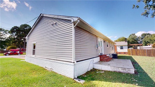 view of side of home with central AC unit, a lawn, and a patio area