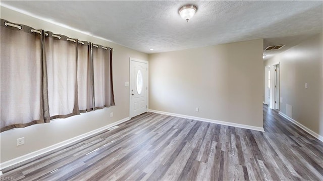 spare room featuring hardwood / wood-style flooring and a textured ceiling