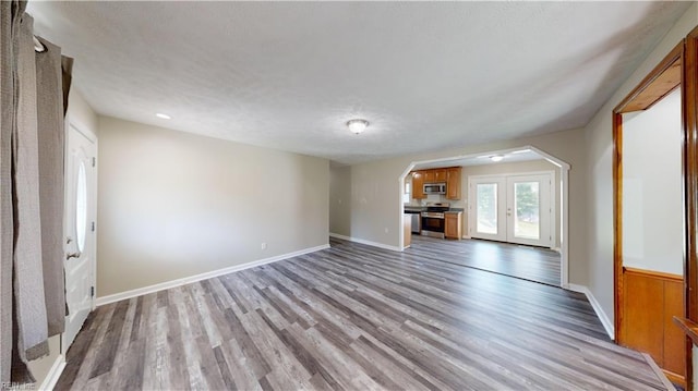 unfurnished living room featuring light wood-type flooring and french doors