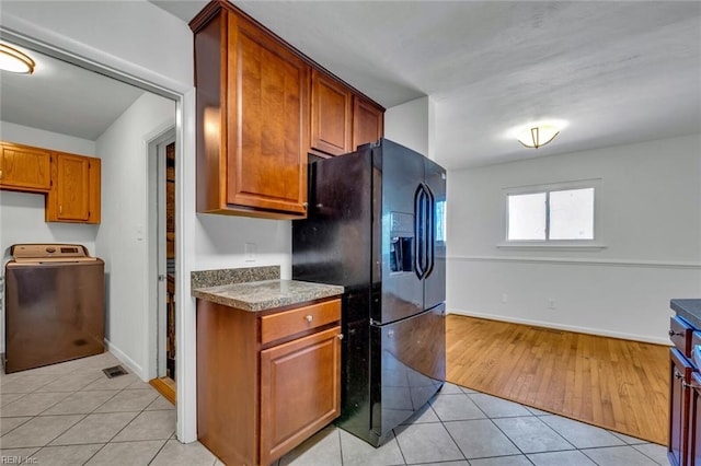 kitchen featuring washer / clothes dryer, light wood-type flooring, and black fridge