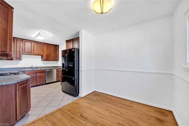 kitchen featuring stainless steel dishwasher, sink, black fridge, and light hardwood / wood-style flooring