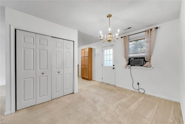 unfurnished bedroom featuring cooling unit, light colored carpet, a closet, and a chandelier