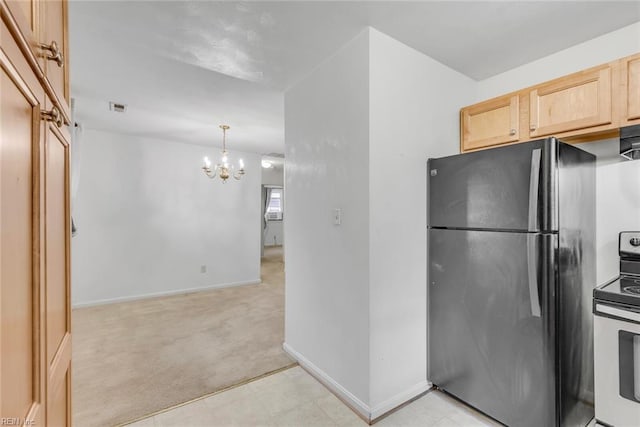 kitchen with light brown cabinets, pendant lighting, black refrigerator, an inviting chandelier, and electric range