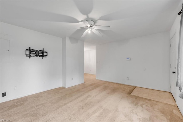 empty room featuring ceiling fan, light colored carpet, and electric panel