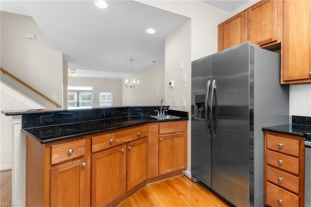 kitchen featuring dark stone countertops, an inviting chandelier, light hardwood / wood-style flooring, decorative light fixtures, and stainless steel refrigerator with ice dispenser