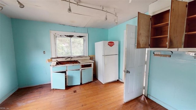 kitchen featuring light wood-type flooring, sink, and white fridge