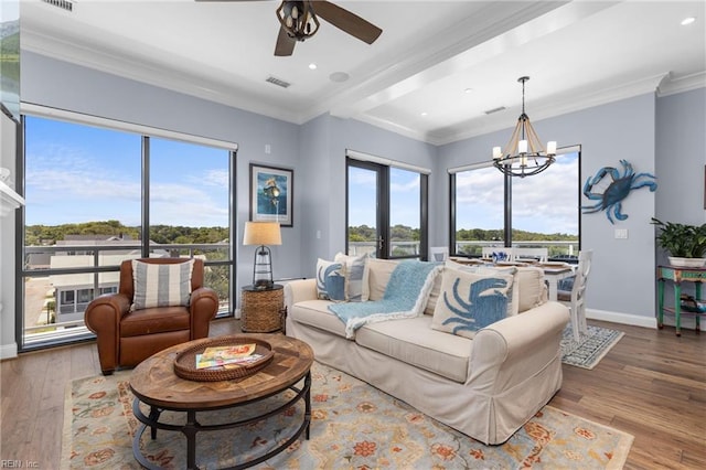 living room featuring ceiling fan with notable chandelier, plenty of natural light, hardwood / wood-style floors, and crown molding