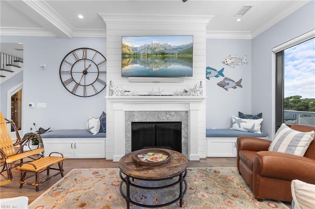 living room with light wood-type flooring, beam ceiling, ornamental molding, and a premium fireplace