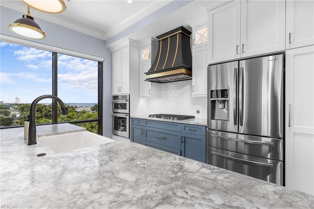 kitchen with appliances with stainless steel finishes, custom range hood, light stone counters, and white cabinets